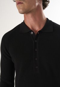 Mustad musta värvi pikad varrukad polo särk ribakudumisega, laia kraega ja viie musta plastiknupuga.