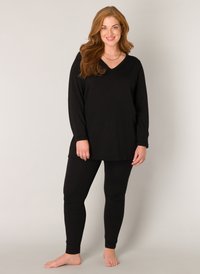 Zwarte longsleeve top met een V-hals en bijpassende zwarte leggings. Zacht materiaal, relaxed fit, eenvoudig ontwerp, en geen patronen of hardware details.