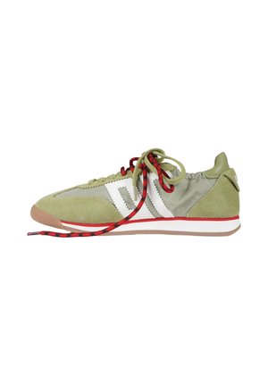Sneaker verde oliva con strisce a zigzag bianche, lacci rossi e neri, rifinitura rossa sulla suola bianca e dettagli in pelle scamosciata.
