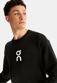Black sweatshirt made of soft fabric featuring a large white logo on the chest. Crew neckline and relaxed fit with ribbed cuffs.