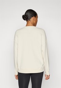 Krém színű, laza fazonú pulóver, kerek nyakkivágással, hosszú ujjakkal és bordázott aljjal, puha, texturált anyagból készült.