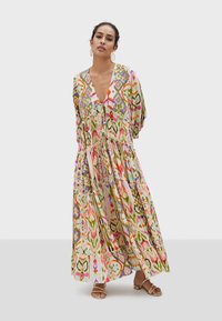 Maxiklänning med V-ringning, färgglada abstrakta mönster i rosa, grönt och gult, med lager av volanger och flödande tyg.