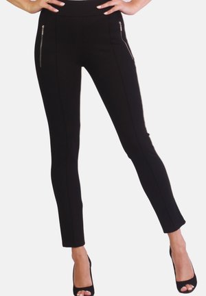 Black fitted pants made of stretchy fabric, featuring two front zippered pockets, sleek lines, and a high waistband, paired with black heels.