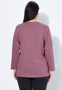 Langsleeve overhemd in mauve, gemaakt van zachte stof. Heeft een relaxte pasvorm met een ronde halslijn en lichte zijsplitsingen, weergegeven vanuit de achterkant.