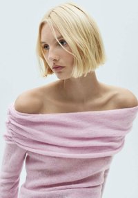 Off-shoulder rosa stickad tröja med en mjuk textur, med draperad design och långa ärmar, som framhäver en avslappnad passform.