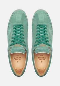 Sneaker verde in suede con lacci piatti, punta arrotondata, fodera in pelle marrone chiaro a contrasto e nome del marchio stampato in oro sul lato.