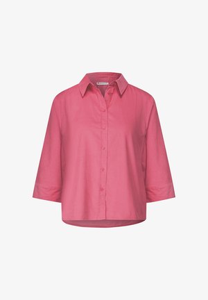 Chemise à manches courtes, boutonnée, en tissu rose vif. Elle possède un col et une coupe décontractée, sans motifs ni embellissements visibles.