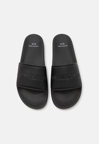 Infradito neri con una tomaia sintetica testurizzata, dotati di logo in rilievo e una soletta liscia. Design semplice senza ulteriori dettagli.