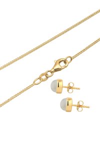 Vergoldetes Schmuckset mit einer dünnen Kette mit Karabinerverschluss und runden Ohrsteckern mit transparentem Stein in goldfarbenen Fassungen.