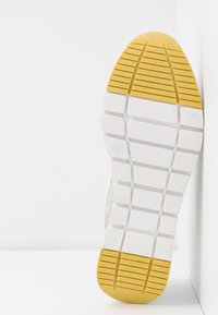 Weiße Sneaker-Sohle mit strukturierter Oberfläche; gelber Gummi-Akzent an der Ferse; verfügt über ein Rautenmuster für Traktion. Größe angegeben als 37.