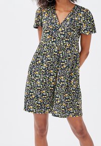 Robe fleurie avec un fond sombre et de petites fleurs jaunes, bleues et vertes. Elle a des manches courtes et un décolleté en V, avec une taille élastique.
