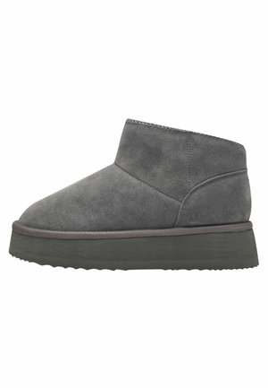 Bottines en suède grises avec un bout rond, semelle plate en caoutchouc et bord de semelle gris contrastant. Texture lisse et design simple.
