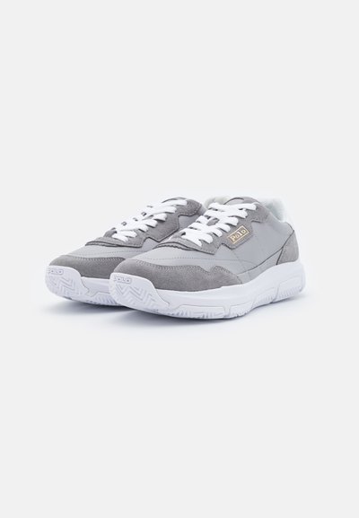 Adidași gri din materiale de suede și plasă, cu accente albe, tălpi texturate și șireturi albe. Prezintă un logo "Polo" în aur.