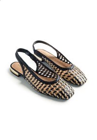 Bailarinas slingback tejidas en negro y beige con tacones bajos y punteras cuadradas redondeadas sobre fondo blanco.