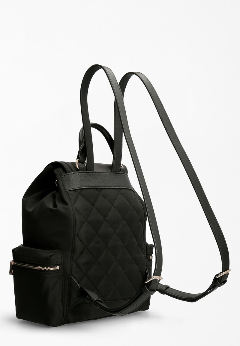 Zaino nero trapuntato realizzato in tessuto morbido con eleganti dettagli in pelle. Presenta spallacci regolabili e una tasca frontale con zip per riporre oggetti.