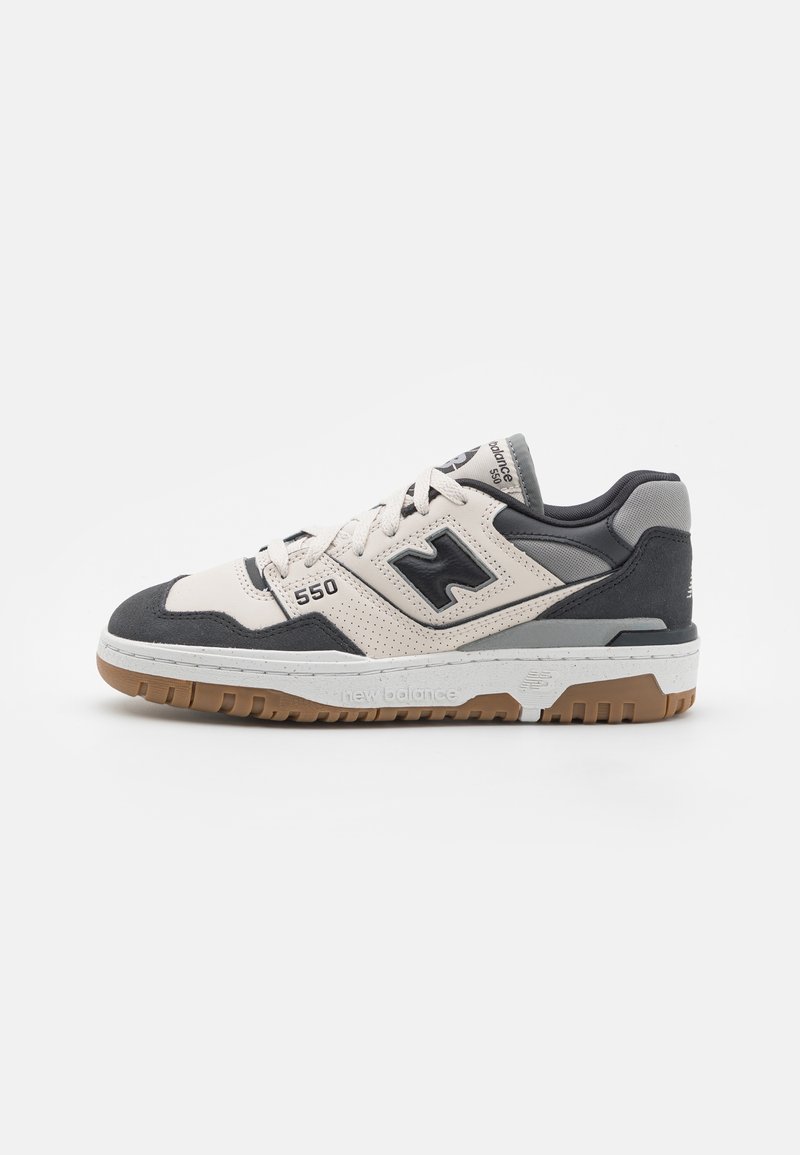 Baskets New Balance 550 blanches et grises avec logo noir, lacets blancs et semelle en caoutchouc marron, vues de côté sur fond blanc.