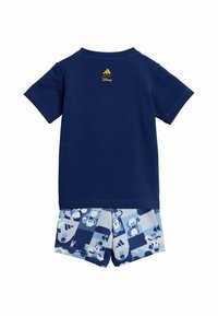 Blå bomullströja med korta ärmar, prydd med en gul Adidas-logotyp. Matchas med ljusblå shorts dekorerade med mönster av Disney-karaktärer.
