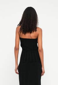 Top negru fără bretele, croială ajustată, țesătură texturată cu dungi verticale, margine dreaptă și guler fără cusături.