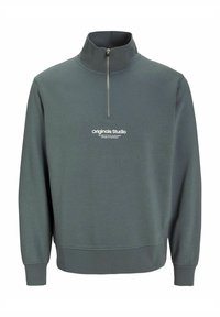 Sweatshirt închis la culoare, cu fermoar pe jumătate, având un guler înalt, mansete ribbate și un grafic alb logo pe piept. Textură a materialului moale și neted.