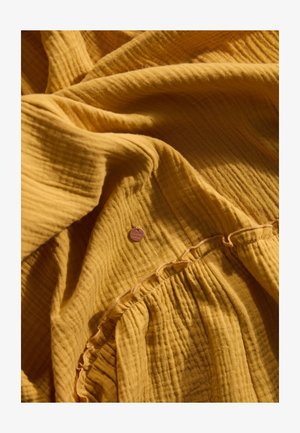 Senfgelbes, strukturiertes Stoffmaterial mit zerknittertem Finish. Verfügt über dezente geraffte Details und ein kleines Markenetikett.