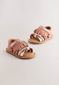 Sandali in suede rosa con dettagli metallici, cinturini intrecciati, dettagli con frange, design con punta aperta e sottopiede imbottito su suola in gomma color biscotto.