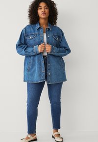 Giacca oversized in denim blu con tasche frontali, chiusure a bottone e vestibilità casual. Abbina a jeans skinny e calzature in contrasto.