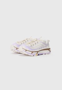 Chaussures de trail en crème, violet clair et marron. Tige texturée avec des rayures contrastées, semelle en caoutchouc robuste dotée de crampons pour une bonne adhérence.