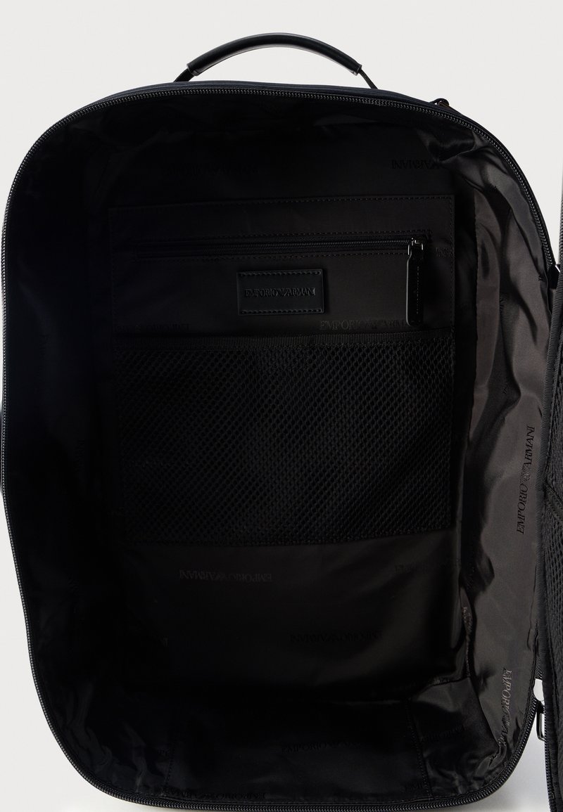 Interno dello zaino nero con tasca con cerniera e scomparto in rete, logo Emporio Armani impresso sulla tasca e sulla fodera.