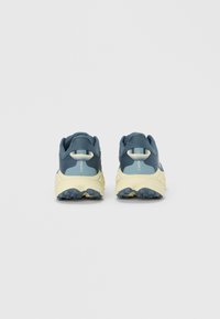 Μπλε και γκρι αθλητικά παπούτσια με διάτρητο πάνω μέρος, μπεζ σόλα, υφασμένο πέλμα και ετικέτα με την ένδειξη "CHALLENGER 8" στη φτέρνα.