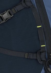 Marineblauwe stoffen rugzaksectie met een verstelbare band, voorzien van een zwarte plastic gesp en neon groene stiksel langs de rand.