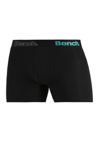 Black boxer shorts made of stretch fabric with a snug fit. Features a contrasting waistband with "Bench." logo in gray and turquoise.