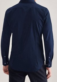 Camicia a maniche lunghe blu navy, con polsini abbottonati, orlo dritto, realizzata in morbido cotone, vista posteriore, con colletto classico e cuciture sottili.