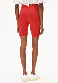 Rode katoenen fietsshorts met een hoge tailleband, een slim fit ontwerp, een gladde textuur en een lengte tot halverwege de dij. Gedragen met witte sneakers.
