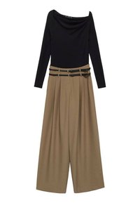 Haut noir à manches longues et décolleté asymétrique associé à un pantalon beige taille haute à large jambe, doté de deux ceintures noires.