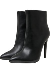 Botas de tobillo de cuero negro con punta afilada, tacón alto de aguja, textura suave y diseño sin costuras. Presenta sutiles detalles de costura.