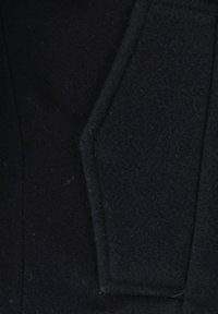 Nahaufnahme eines dunkelblauen Wollmantel-Revers mit sauberen, scharfen Kanten und sichtbaren Steppnähten.