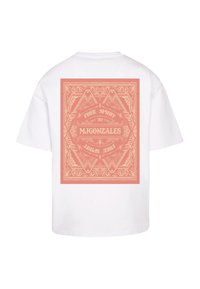 White short-sleeve t-shirt featuring a large pink graphic design on the back with intricate patterns and text saying “FREE SPIRIT 2024 M.GONZALES.”
