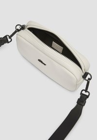 Weiße Kunstleder rechteckige Tasche mit schwarzem Innenraum, Reißverschluss und verstellbarem schwarzen Tragegurt. Besitzt ein kleines Logo auf der Vorderseite.