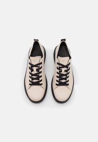 Light beige leather sneakers with black laces and a black sole. Round toe with minimalist design, featuring no visible logos or patterns.