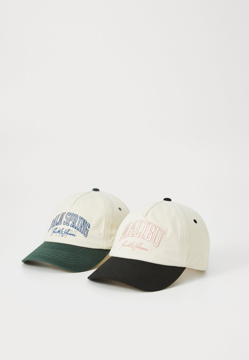 Two baseball caps; one cream with blue "PALM SPRING" text and a green visor, the other cream with pink "MALIBU" text and a black visor.