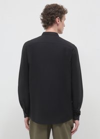 Chemise noire à manches longues avec col boutonné, tissu lisse et ourlet droit. Dispose de manches avec poignets et d'un design minimaliste.