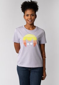 Lavendel Baumwoll-T-Shirt mit einem Katzen-Graphic in Weiß und Gelb, auf einem Hintergrund mit Farbverlauf in Sonnenuntergangsfarben. Kurze Ärmel und runder Ausschnitt.