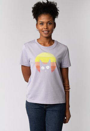 T-shirt en coton lavande avec un graphique de chat en blanc et jaune, sur un fond dégradé de couleurs de coucher de soleil. Manches courtes et encolure ronde.