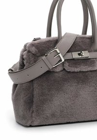 Grå håndtaske lavet af plush pels-lignende materiale, struktureret form, dobbelt håndtag og en aftagelig læderrem med metal spænde og detaljer.