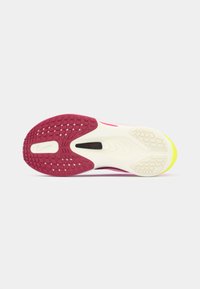 Podeszwa buta biegowego Nike z teksturowaną różową gumową podeszwą, kremową podeszwą środkową i żółtym czubkiem. Posiada czarną metkę z napisem "FLYPLATE".