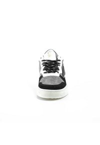 Vue de face d'une chaussure de sport grise et noire avec une semelle blanche et des lacets noirs sur fond blanc.
