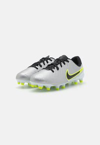 Bottes de football argentées avec une finition texturée, lacets noirs et éclats de jaune néon vif sur le swoosh et la semelle. Semelle extérieure à multi-pointes.