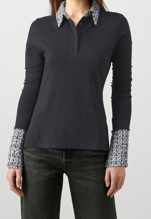 Polo à manches longues en coton bleu marine foncé avec col et poignets à motifs blancs et noirs, doté d'une patte de boutonnage et d'une coupe ajustée.