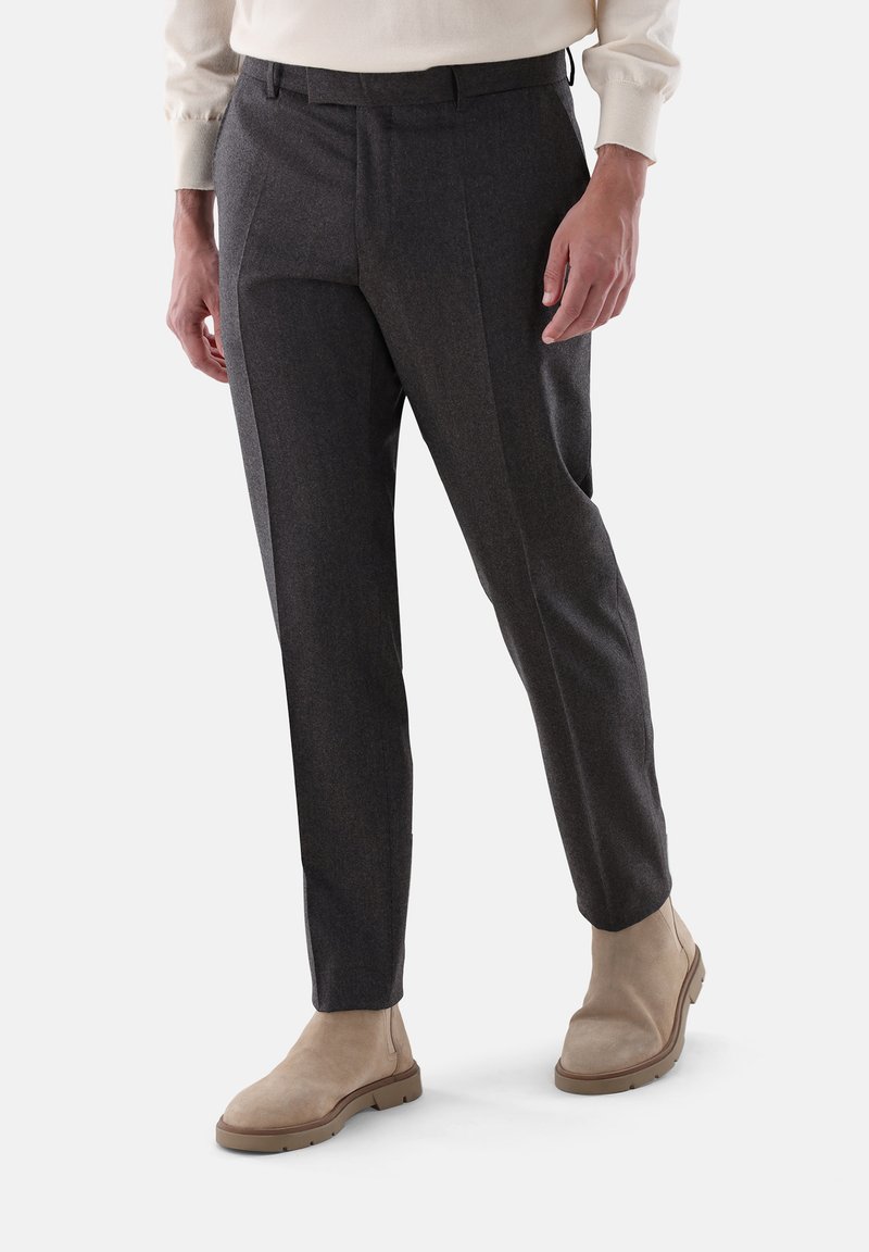 Dunkelgraue maßgeschneiderte Hose aus strukturiertem Stoff, mit einem Gürtelloops Bund und Seitentaschen, kombiniert mit beigen Knöchelstiefeln.