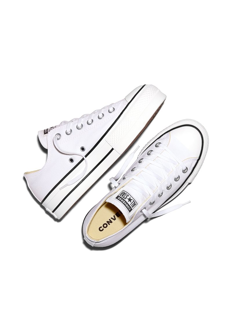 Coppia di sneakers Converse All Star basse bianche con dettaglio a striscia nera e lacci bianchi su sfondo bianco.